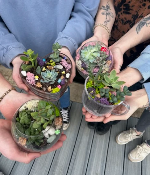 Friends holding hand-decorated terrariums together