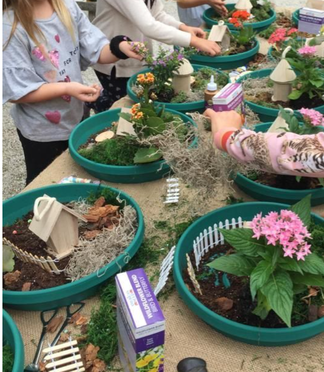 Children planting flowers and decorating fairy gardens in large pots