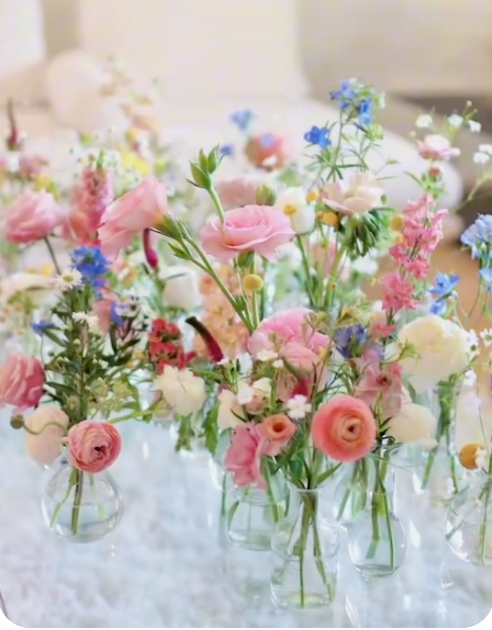 Rows of small glass vases filled with colorful cut flowers